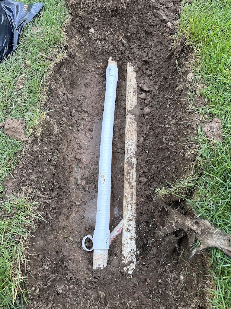 An open trench exposing an underground pool pipe during a repair